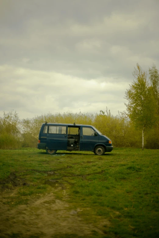 an old van with its front door open sitting in a field