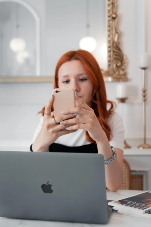 a woman looking at her phone while on the computer