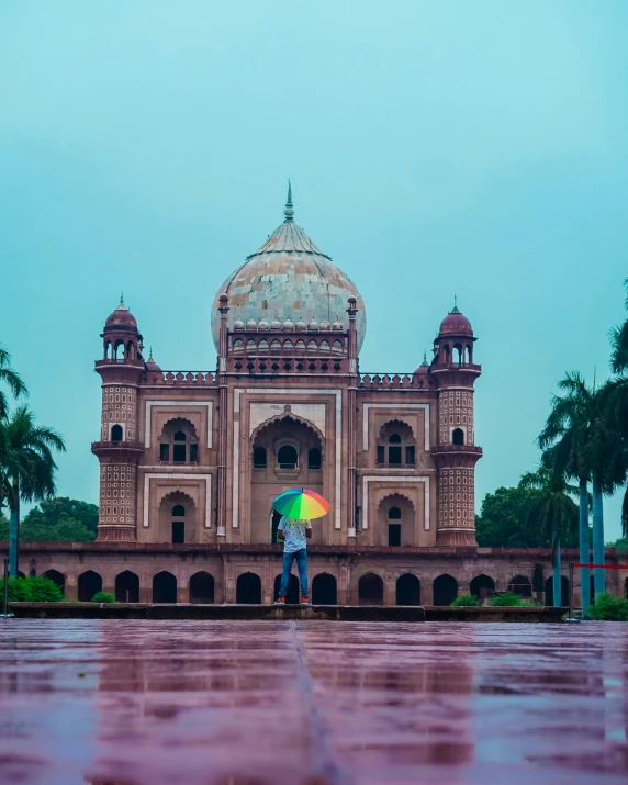 the person has a colorful umbrella on the wet ground