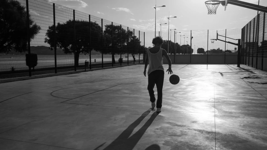 a person walking across a basketball court with a ball