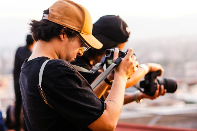 a man with a camera, taking pictures with other people in the background