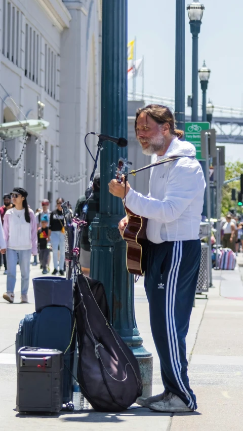 a man in white jacket holding a guitar next to pole