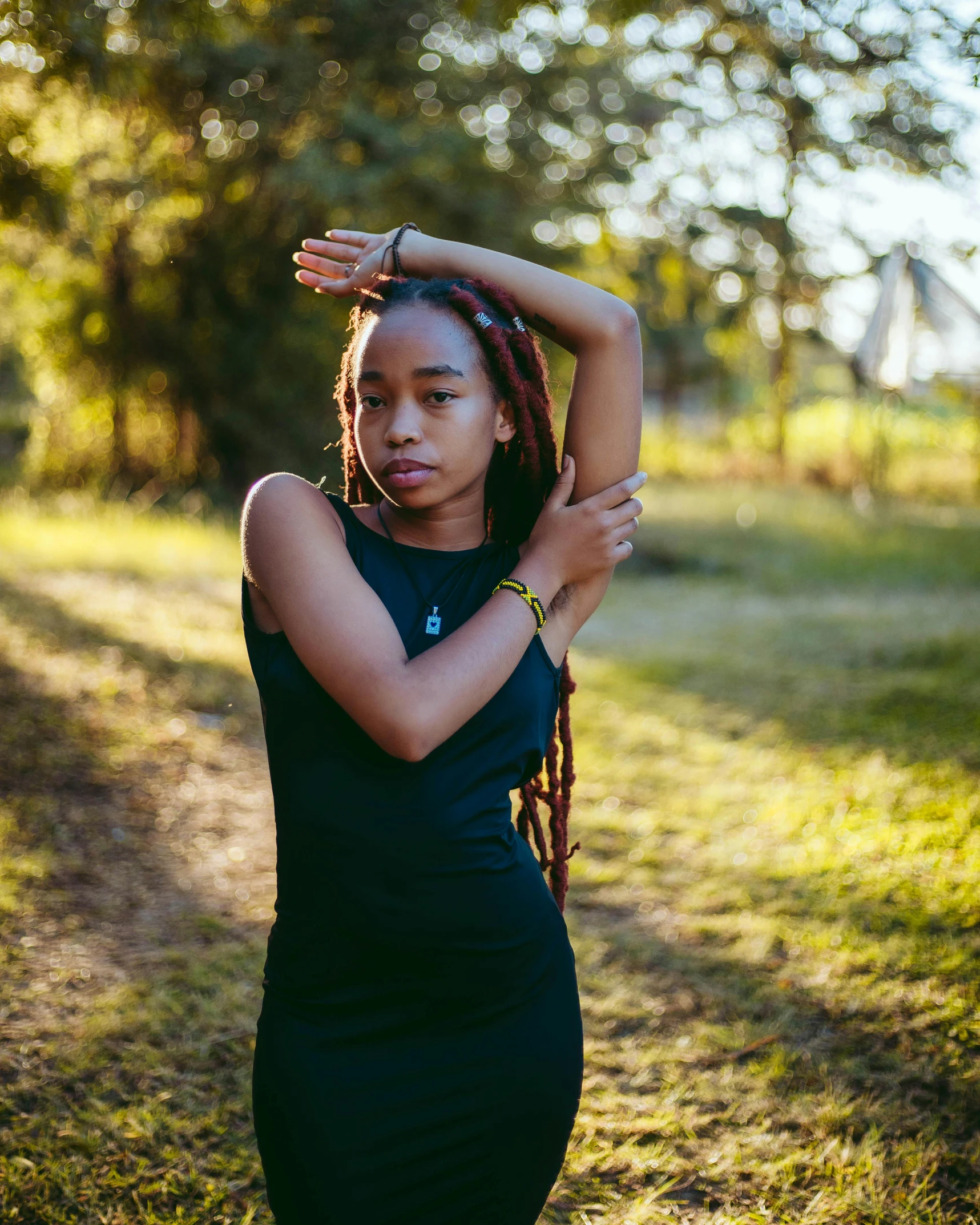 a woman standing on a dirt road, with her arms stretched up