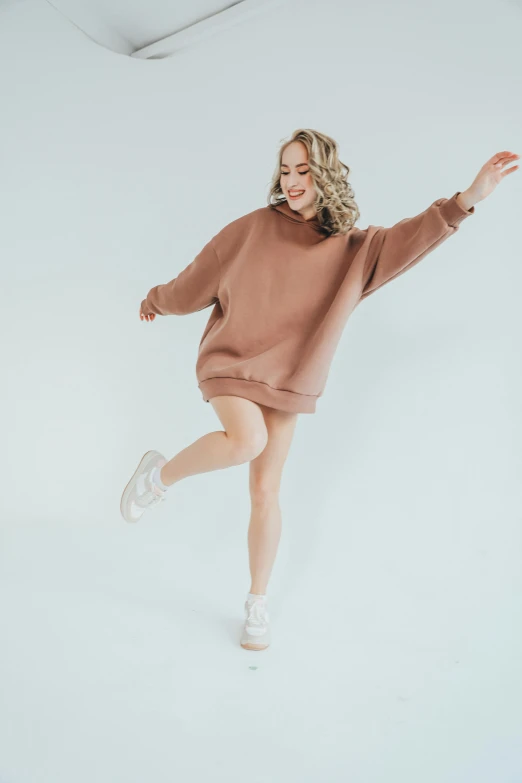 a woman wearing a brown sweatshirt dress and white tennis shoes