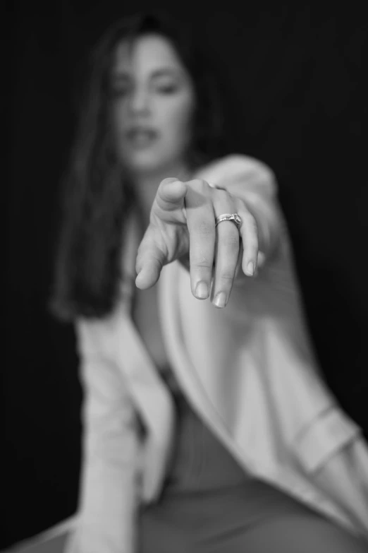 a woman pointing out her finger while wearing a white shirt