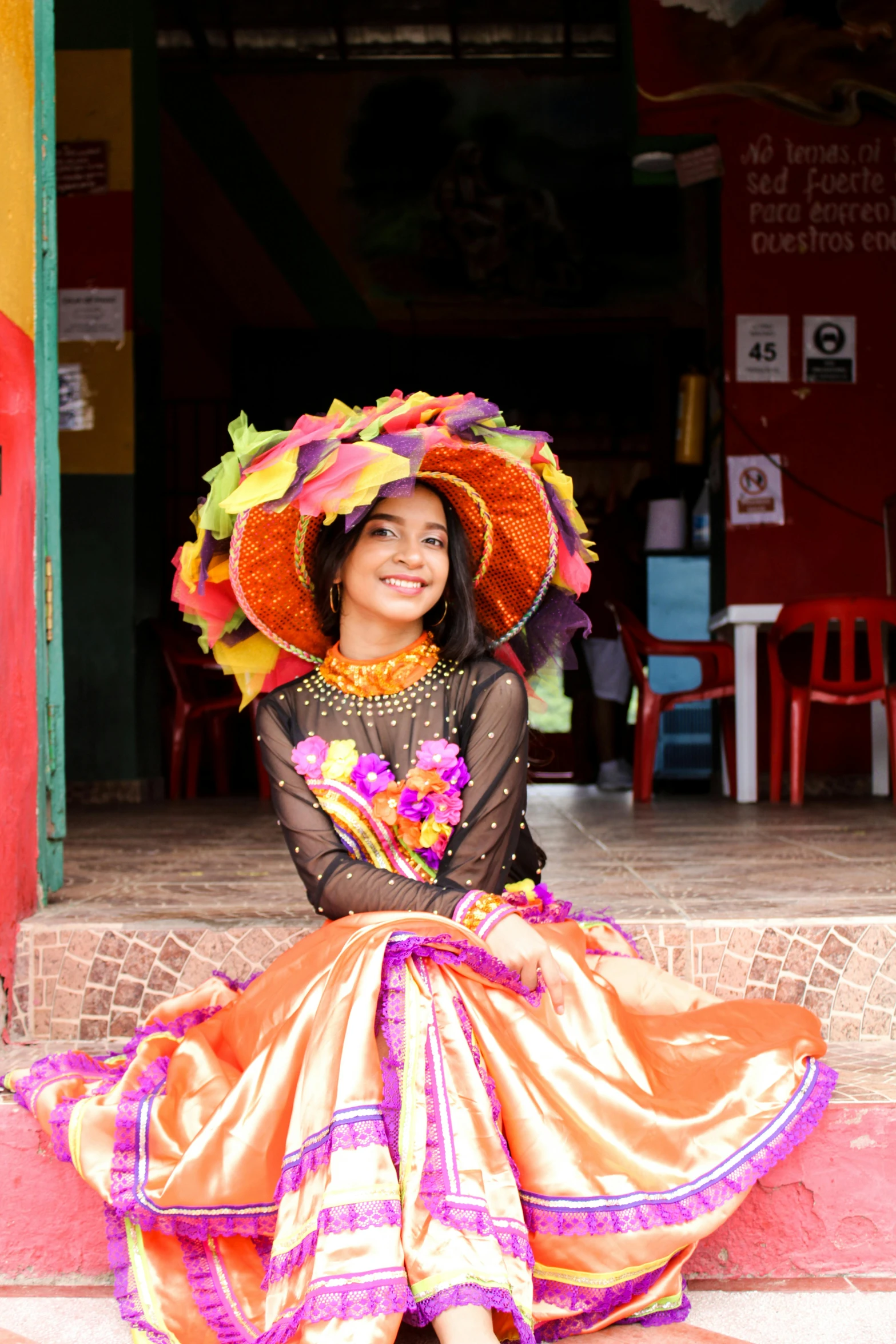 a girl with a colorful hat is sitting down