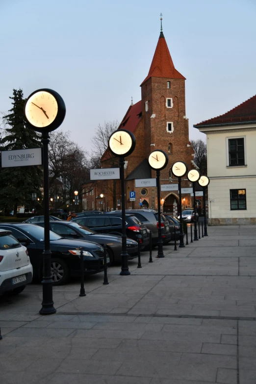 many cars parked on the sidewalk near a building with a clock on it