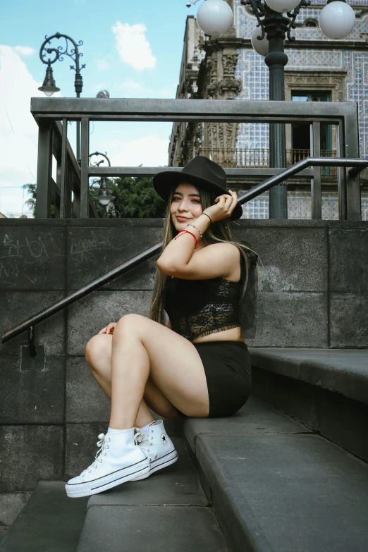 a woman in black sitting on some steps wearing tennis shoes