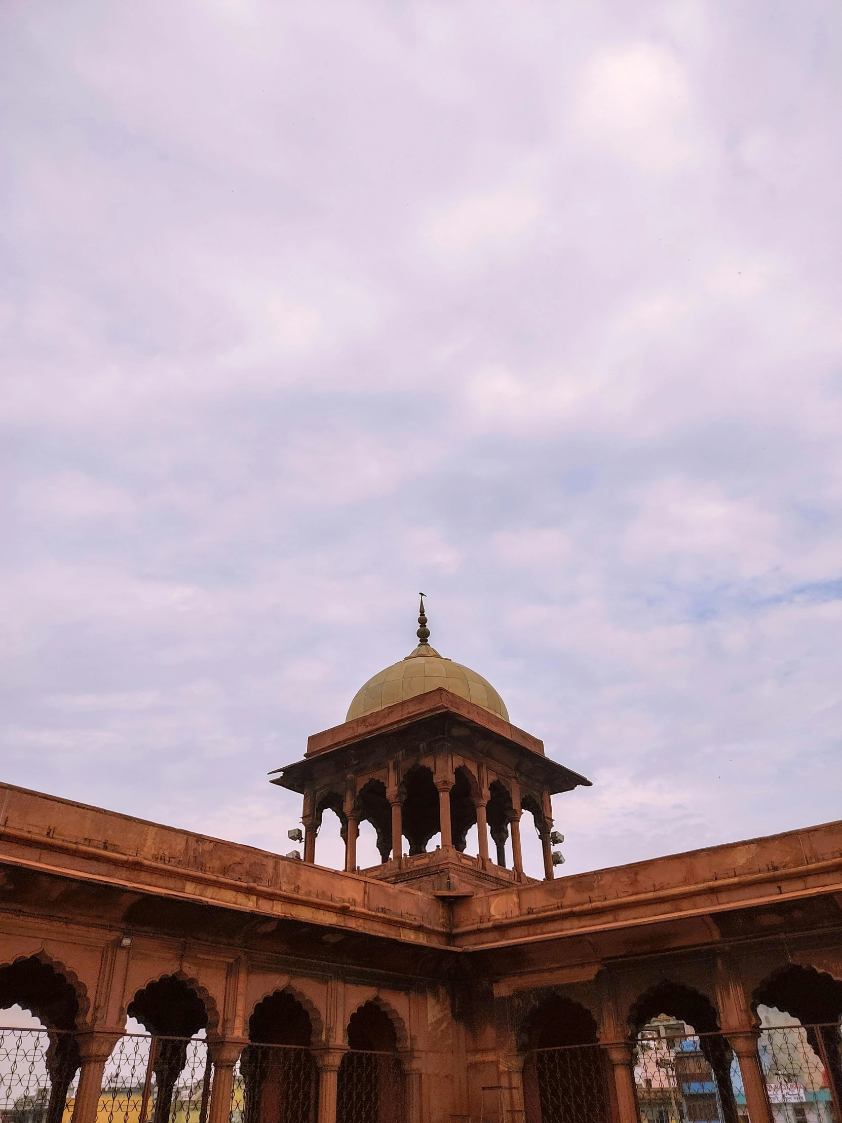 a gazebo with many arches and pillars, under a cloudy sky