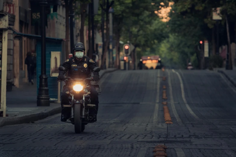 motorcycle rider with face mask driving down street