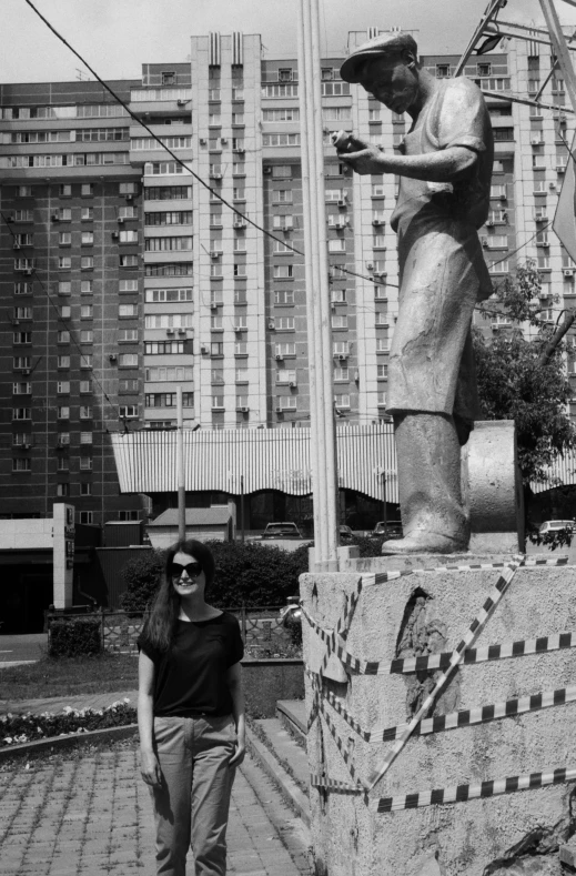 black and white pograph of a woman standing next to a statue