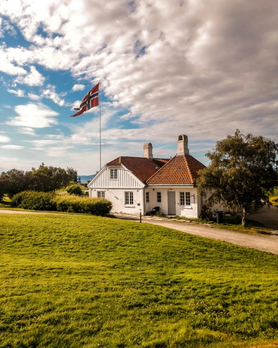 a flag flies above a house near a grassy area