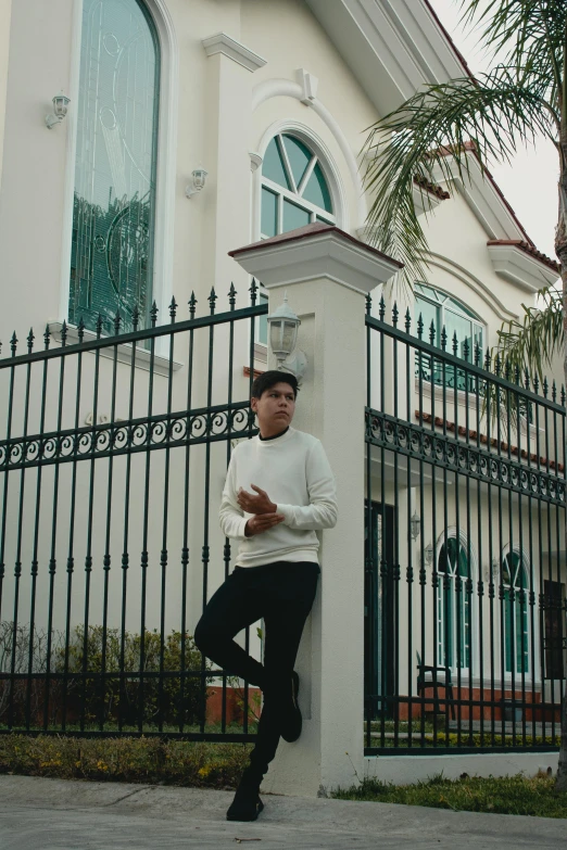 a man poses next to a wrought iron gate