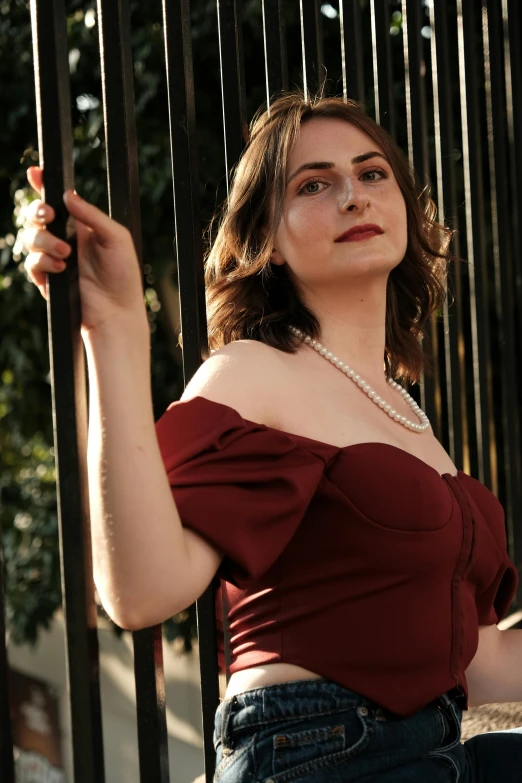 a woman is standing behind a fence with a cigarette in her hand