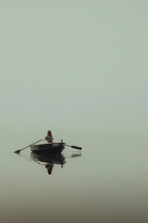 a person is in a boat on a foggy lake