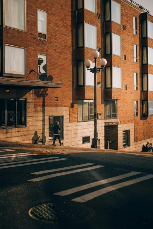 a man walking past a tall brick building with windows