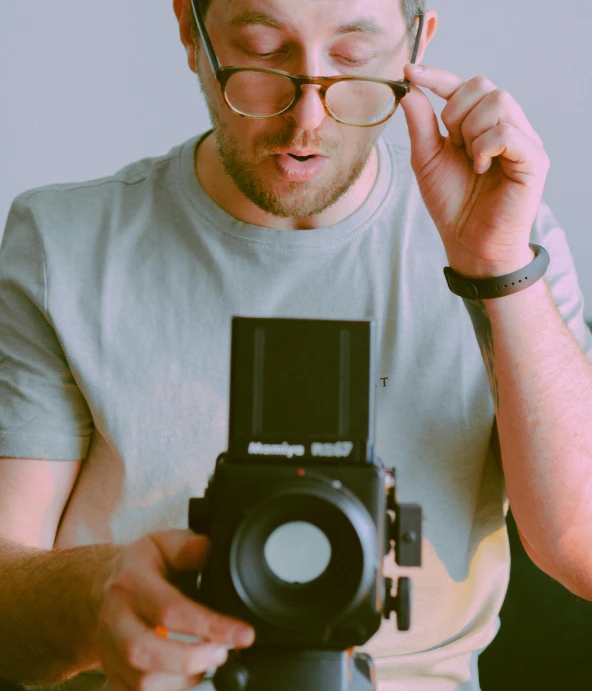 a man wearing glasses while holding a camera