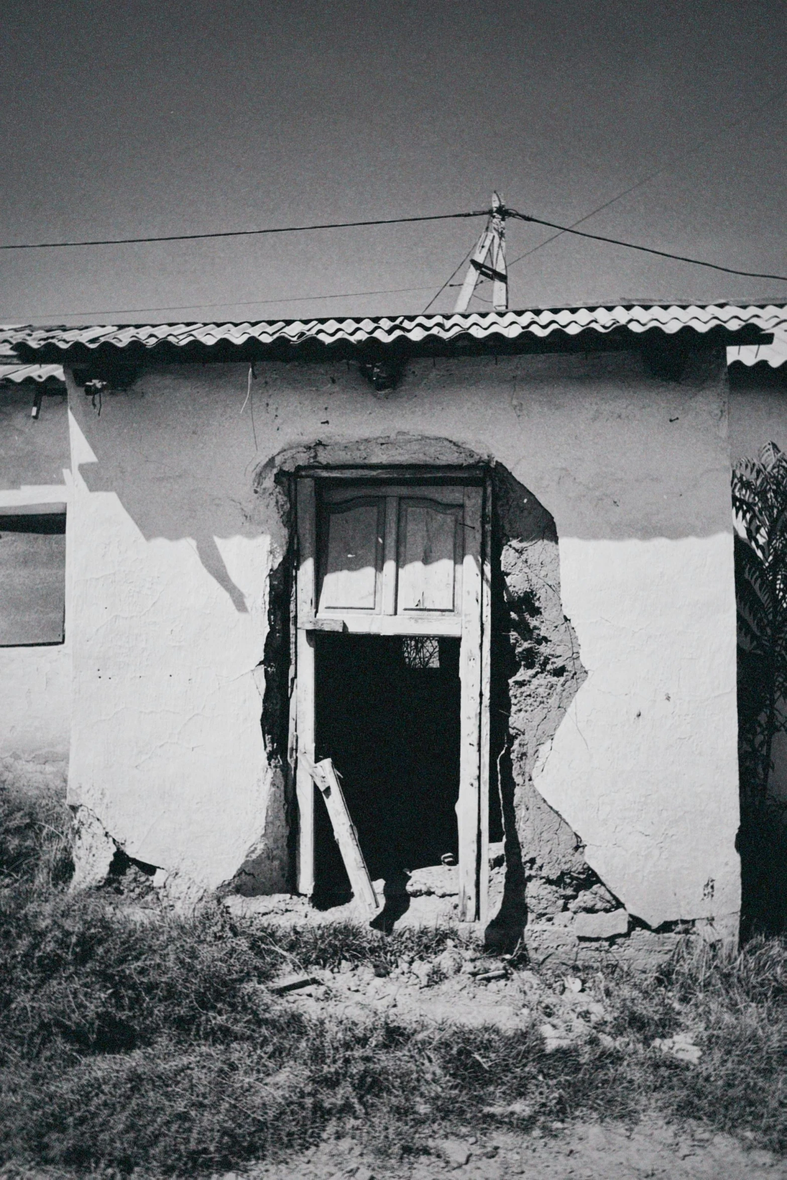 a black and white po of an old, rundown door in an adobe building