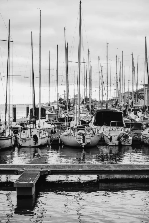 an assortment of sailboats are parked in the water near a dock