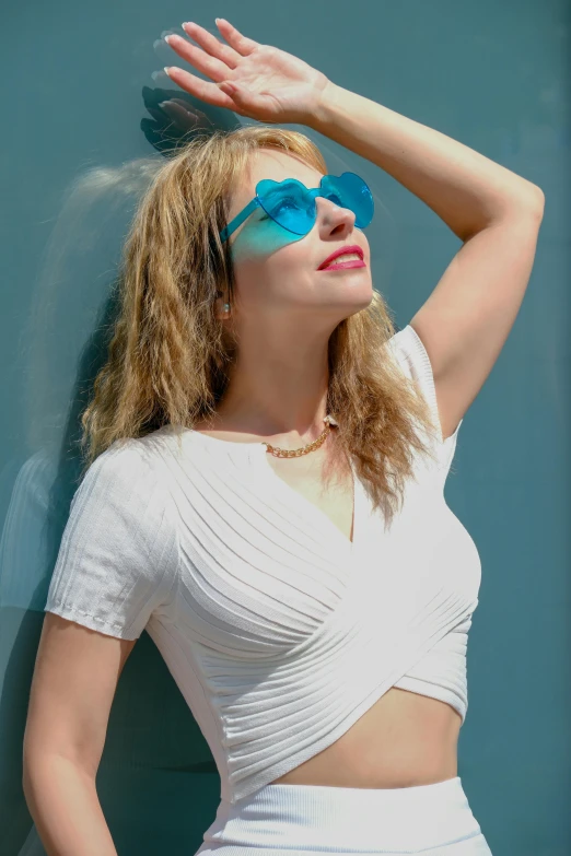 woman in white and blue sunglasses leaning against wall