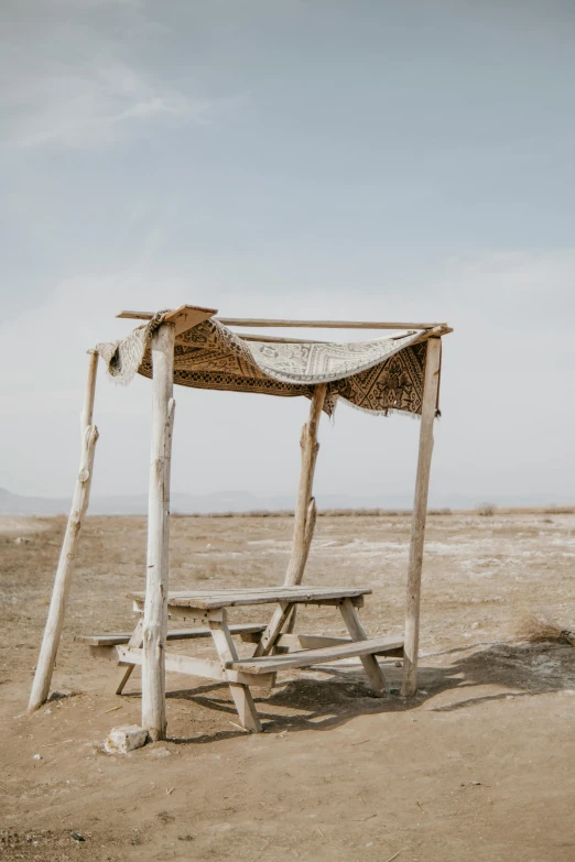 a wooden and roped out gazebo and table on an empty landscape