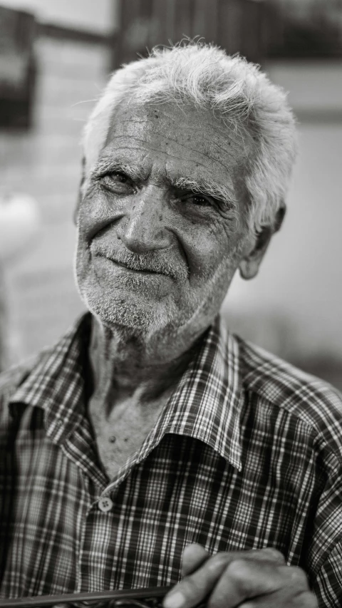 an elderly man with his hands folded while standing next to a tree