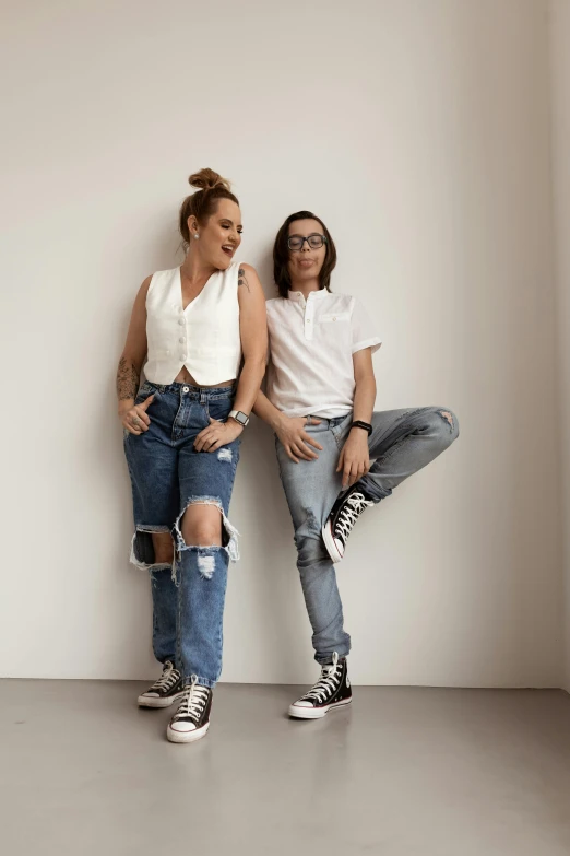 two woman posing against the wall with their legs out