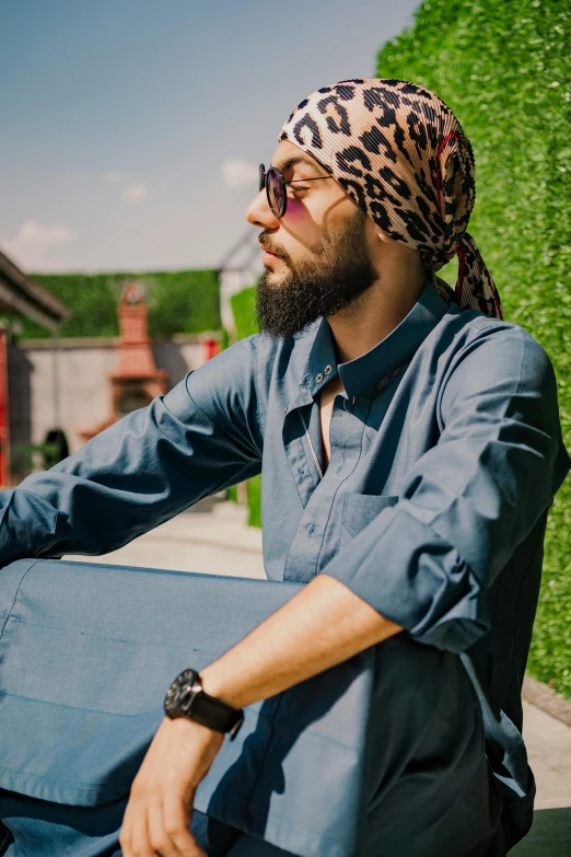 a man with a scarf on sits outside