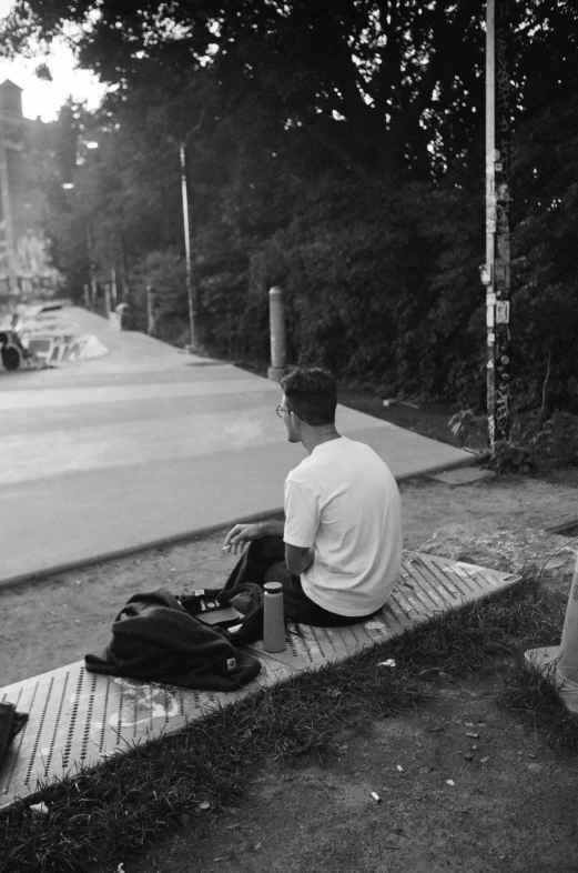 a man sitting on the edge of a street looking at cars passing by