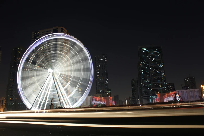 a ferris wheel in the city with lights streaking by at night