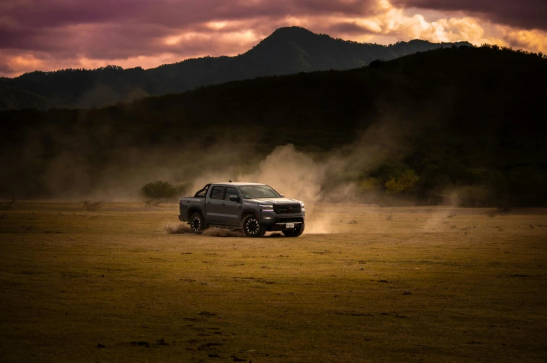 a black pick up truck driving across a field