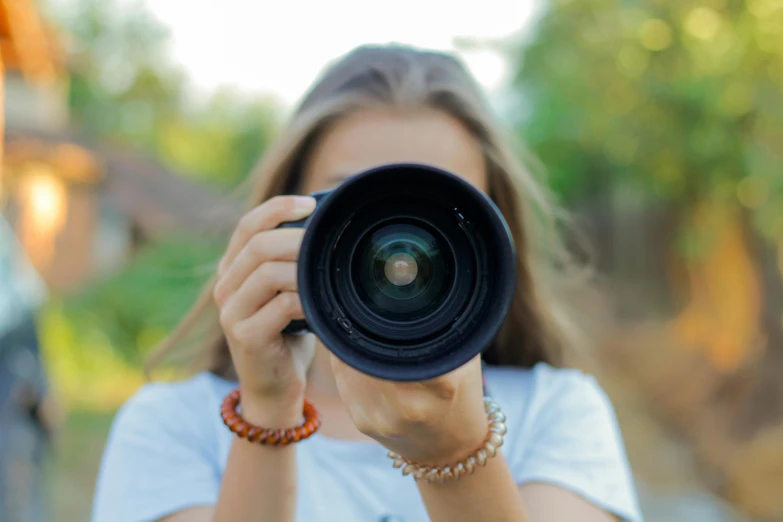 a woman holding up a camera lens