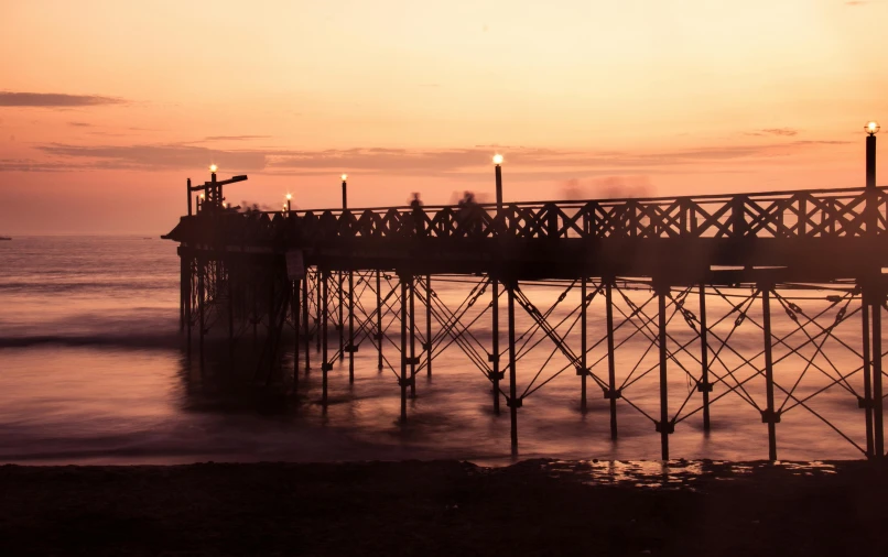 sunset, silhouette of a pier and pier lights in the water