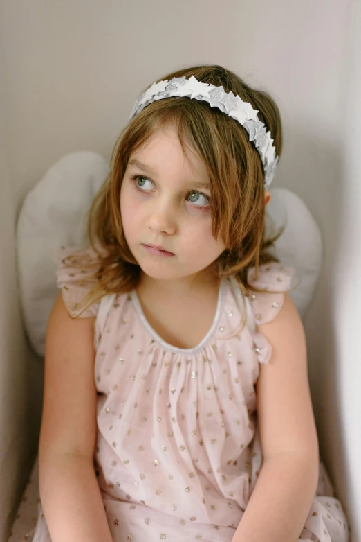 a little girl sitting on top of a bench wearing a headband