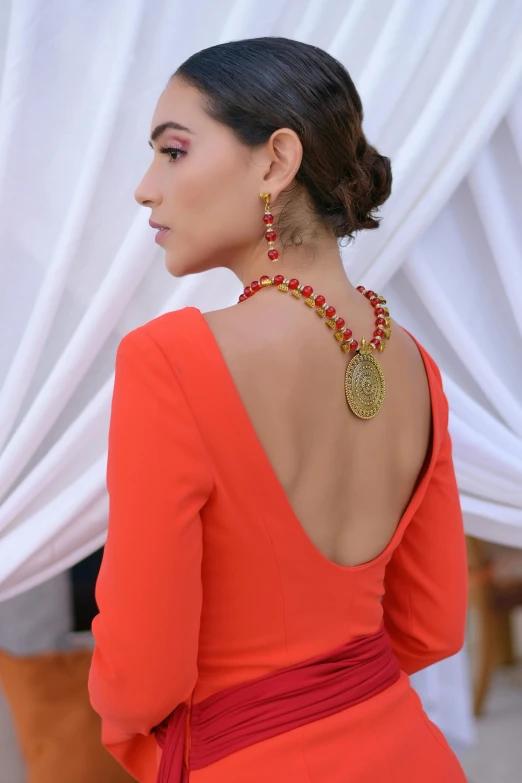 a woman wearing an orange dress with gold accents