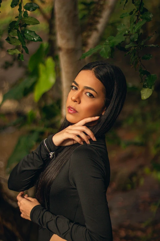 a young woman posing under the leaves of a tree