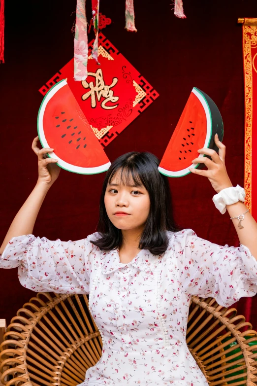 a woman holding up two red paper fans