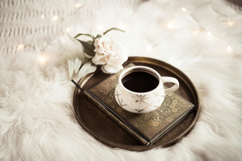 a white plate with a cup of coffee and some white flowers