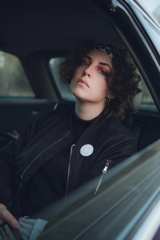 a girl sitting in the front seat of a car, looking out of the window