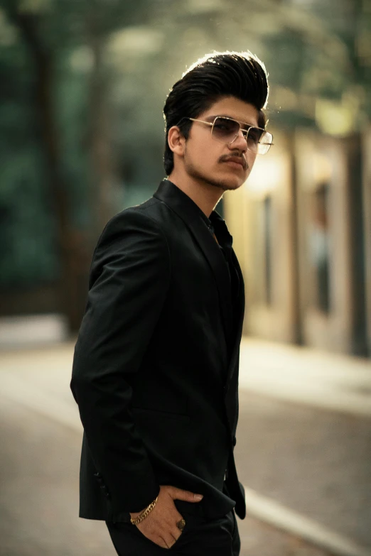 a man wearing dark suit and sunglasses standing outside