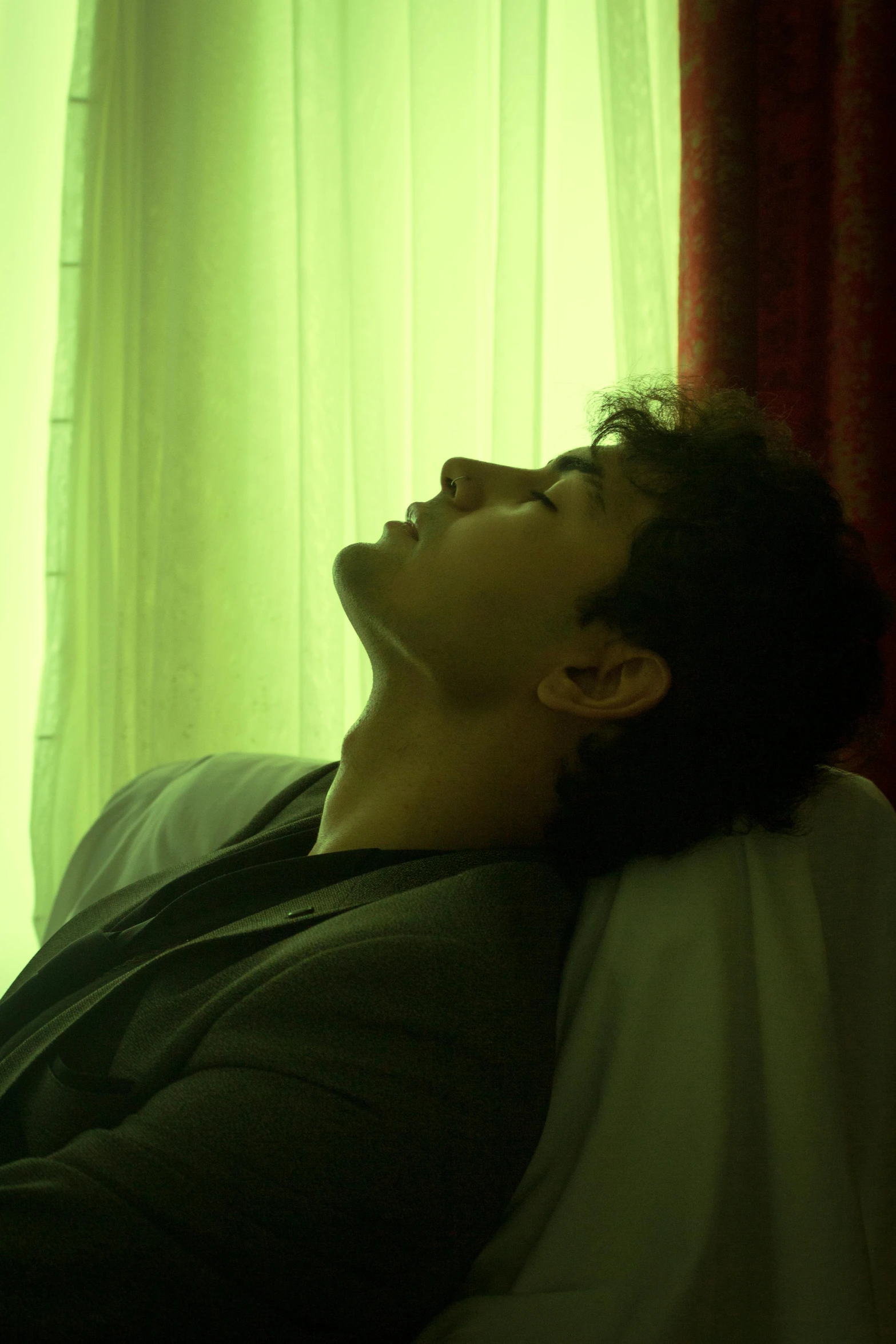 a young man sleeping in front of a window