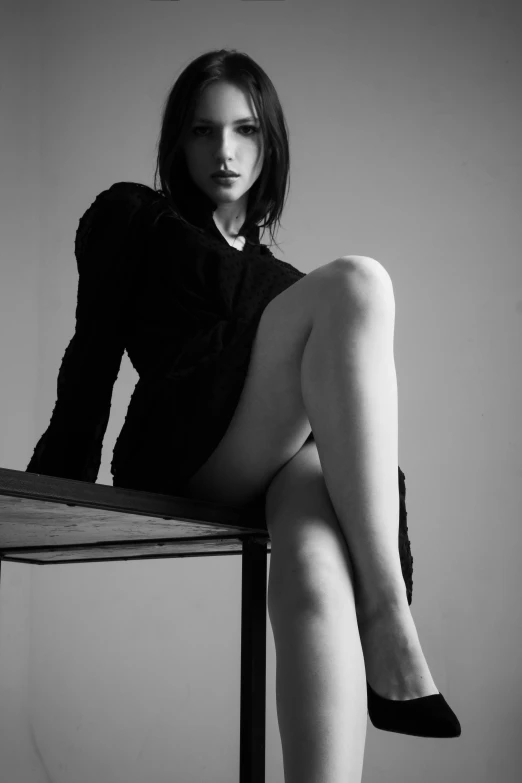 black and white image of a woman sitting on a stool