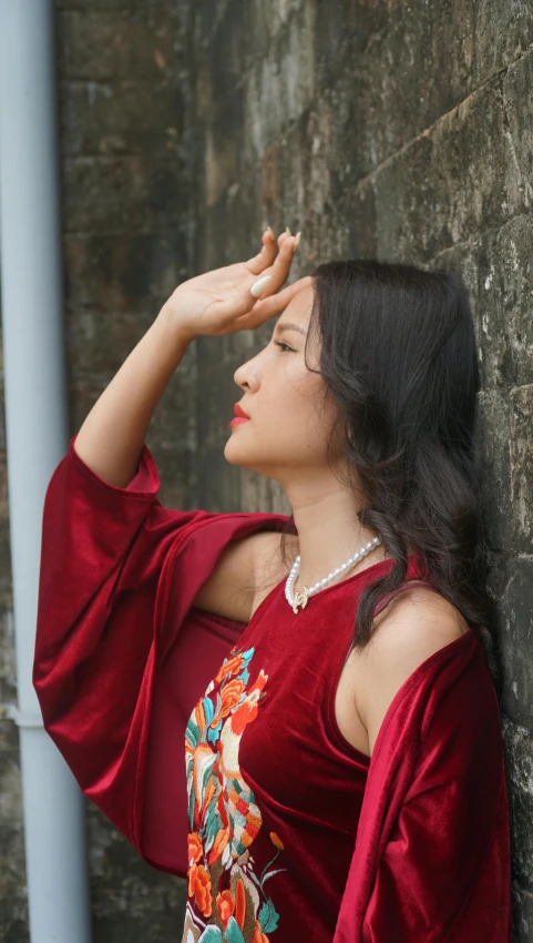 woman in red dress standing by a stone wall