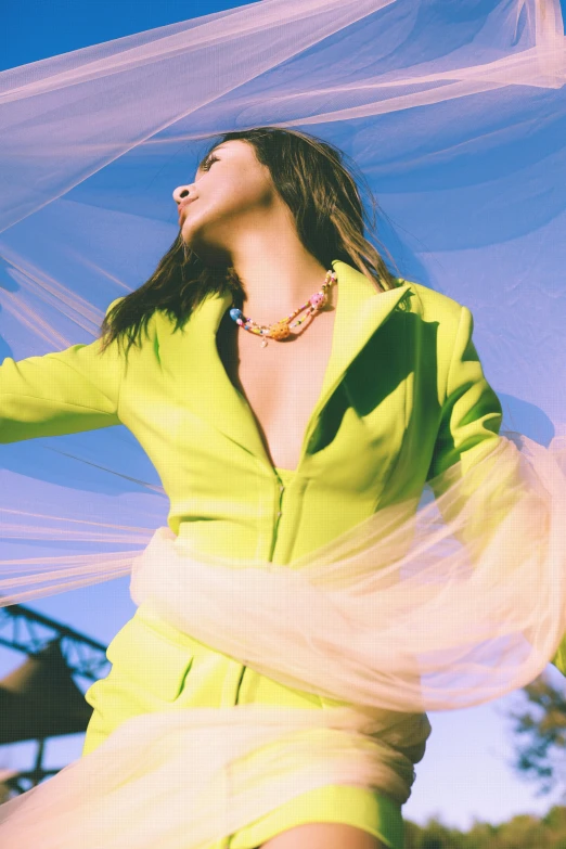 a woman in a yellow dress poses with her hands over her head