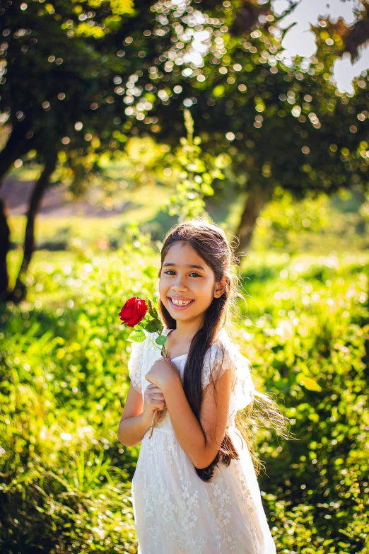 girl in the woods holding a flower and smiling