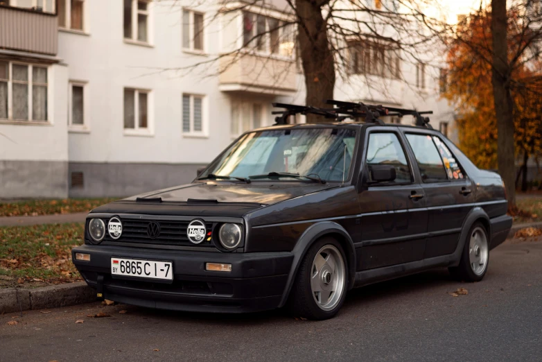 an old black car parked in front of a house with some trees