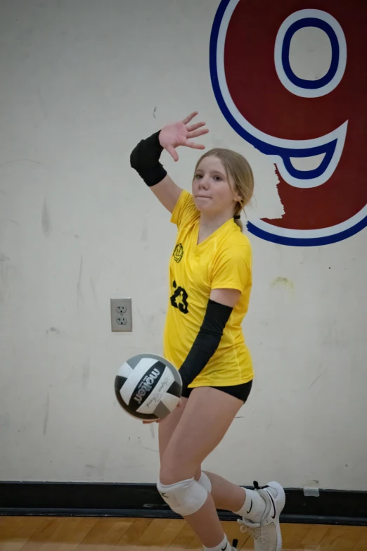 woman holding volleyball while standing on hard wood floor