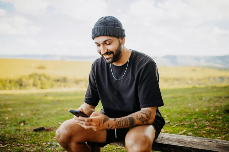 a man sitting on a wooden bench while looking at his cell phone