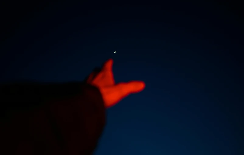 a person pointing towards a plane and a dark blue sky