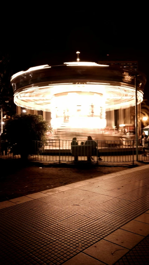 some people are sitting outside a carousel